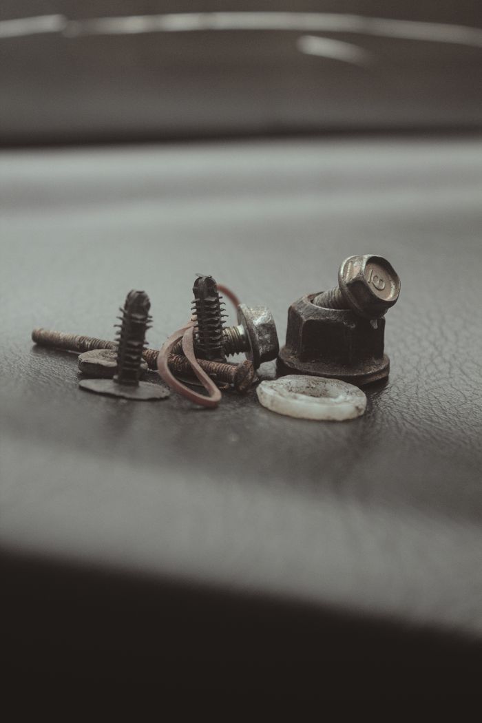 Detailed close-up of various metal screws and bolts on a textured surface, ideal for industrial themes.